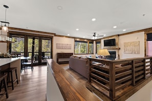 A modern interior with a kitchen, dining area, and living space, featuring wooden beams, large windows, and a fireplace. - Sk1865-2 (Keystone)