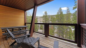 Une terrasse en bois avec des tables de pique-nique et une vue sur un paysage montagneux.