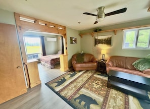 A cozy living room with a sofa, a coffee table, a rug, and a ceiling fan.