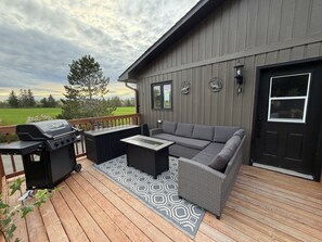 A deck with a grill, a sofa, and a table.