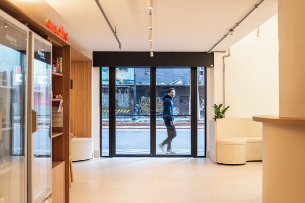 Un interior moderno con una recepción, una puerta de cristal y vistas a la calle.