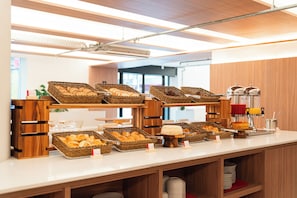 Disposição de buffet com diversos alimentos e um dispensador de sucos.