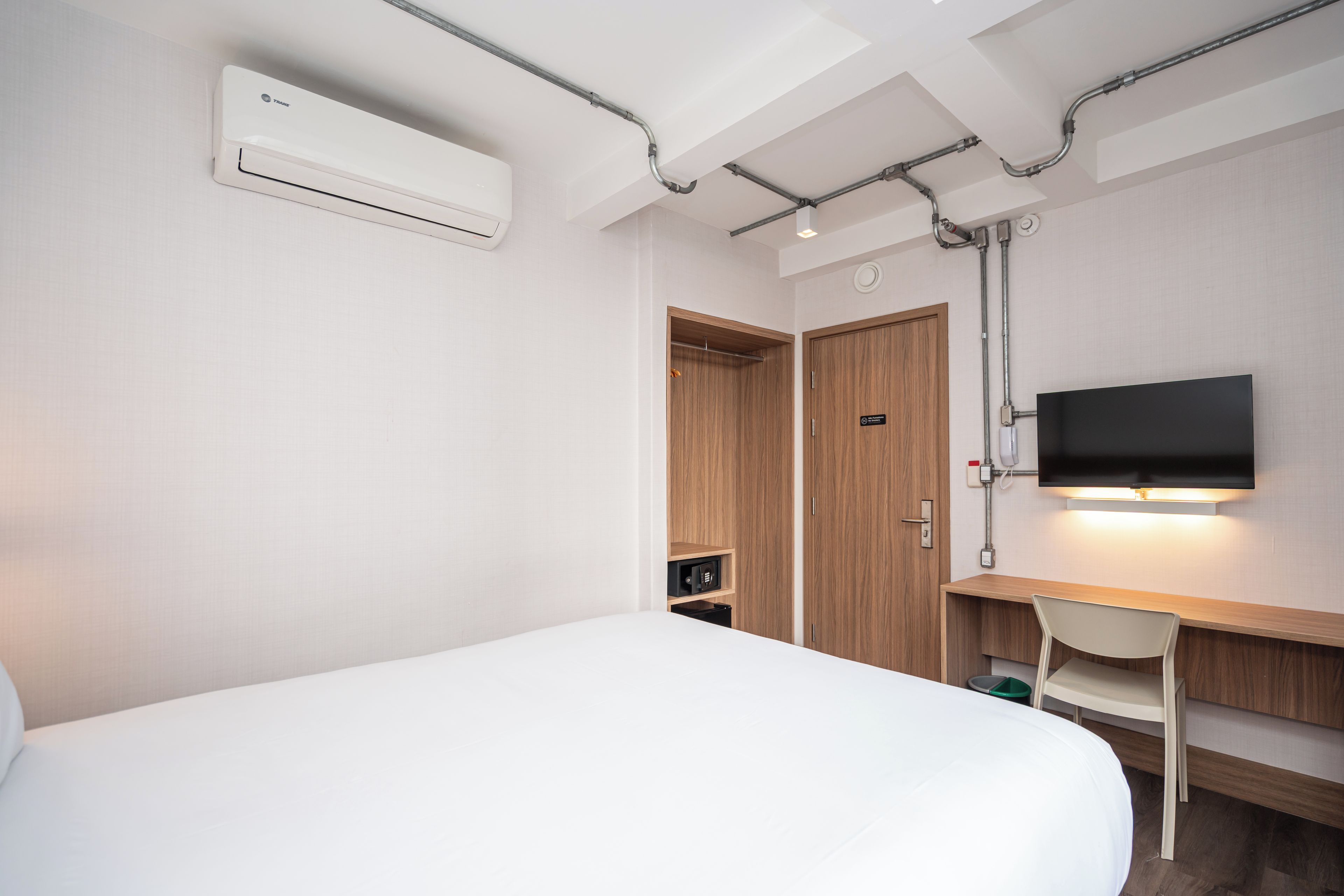 A hotel room with a bed, a desk, a television, and a wardrobe.