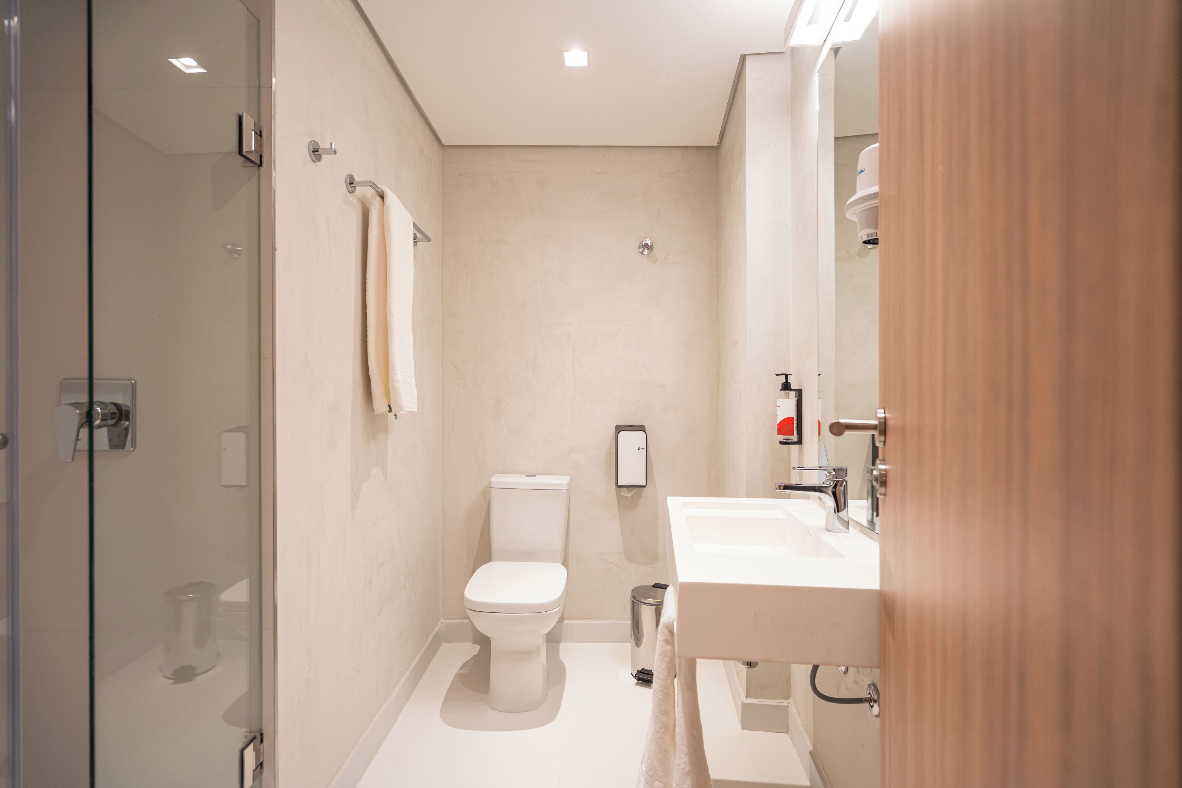 A modern bathroom with a glass shower enclosure, a toilet, and a sink with a mirror.