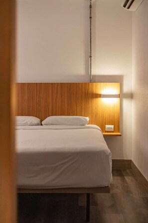 A hotel room with a wooden headboard, a bedside lamp, and a bed with white bedding. - Hotel Moov São Paulo (São Paulo)