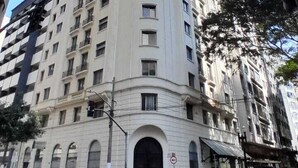 Un immeuble à plusieurs étages doté d’une façade incurvée, d’une entrée imposante et surplombant un ciel dégagé.