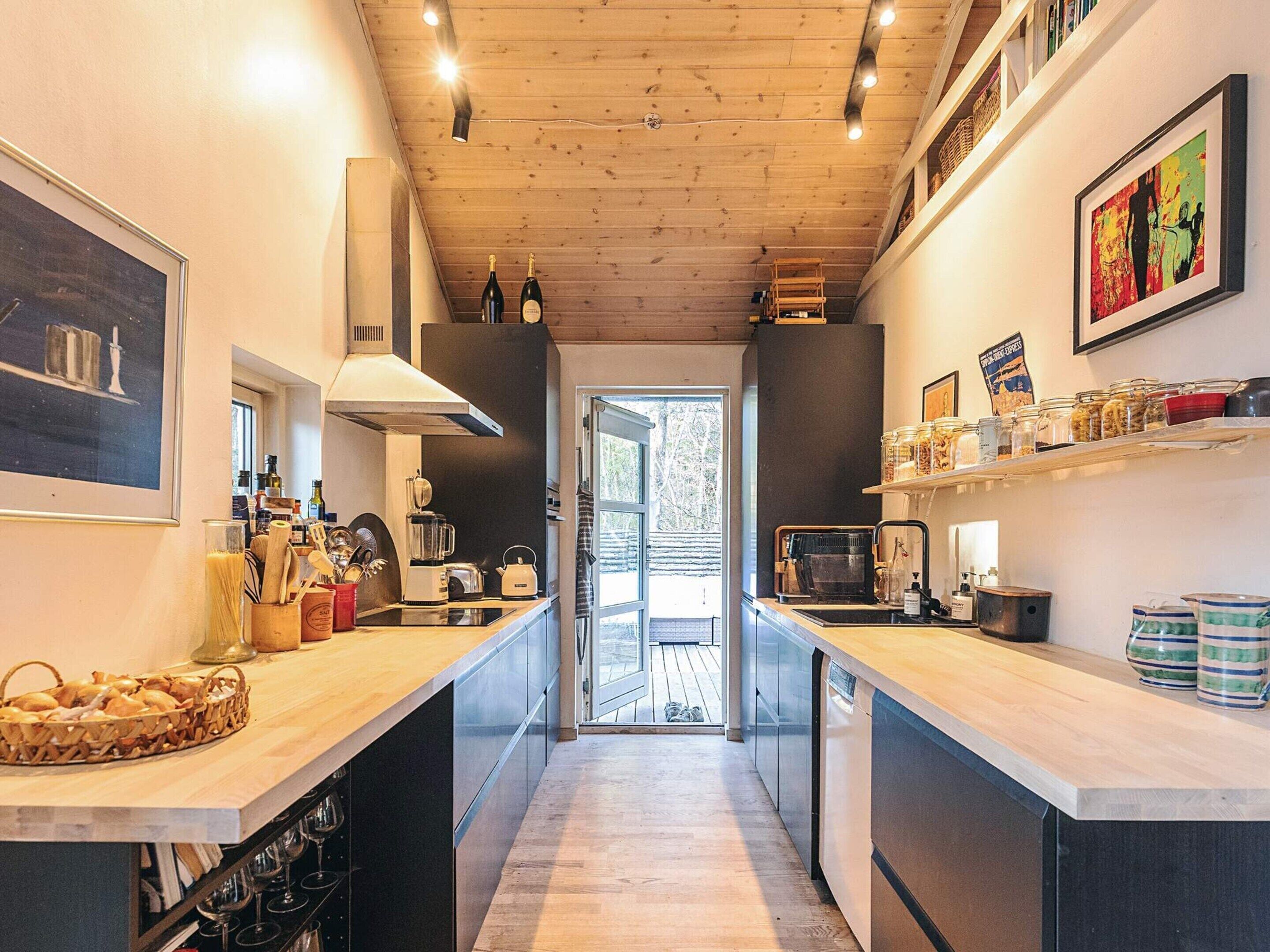 A modern kitchen with wooden countertops, a central island, and a view to a deck.