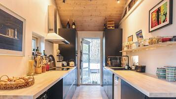 A modern kitchen with wooden countertops, a central island, and a view to a deck.