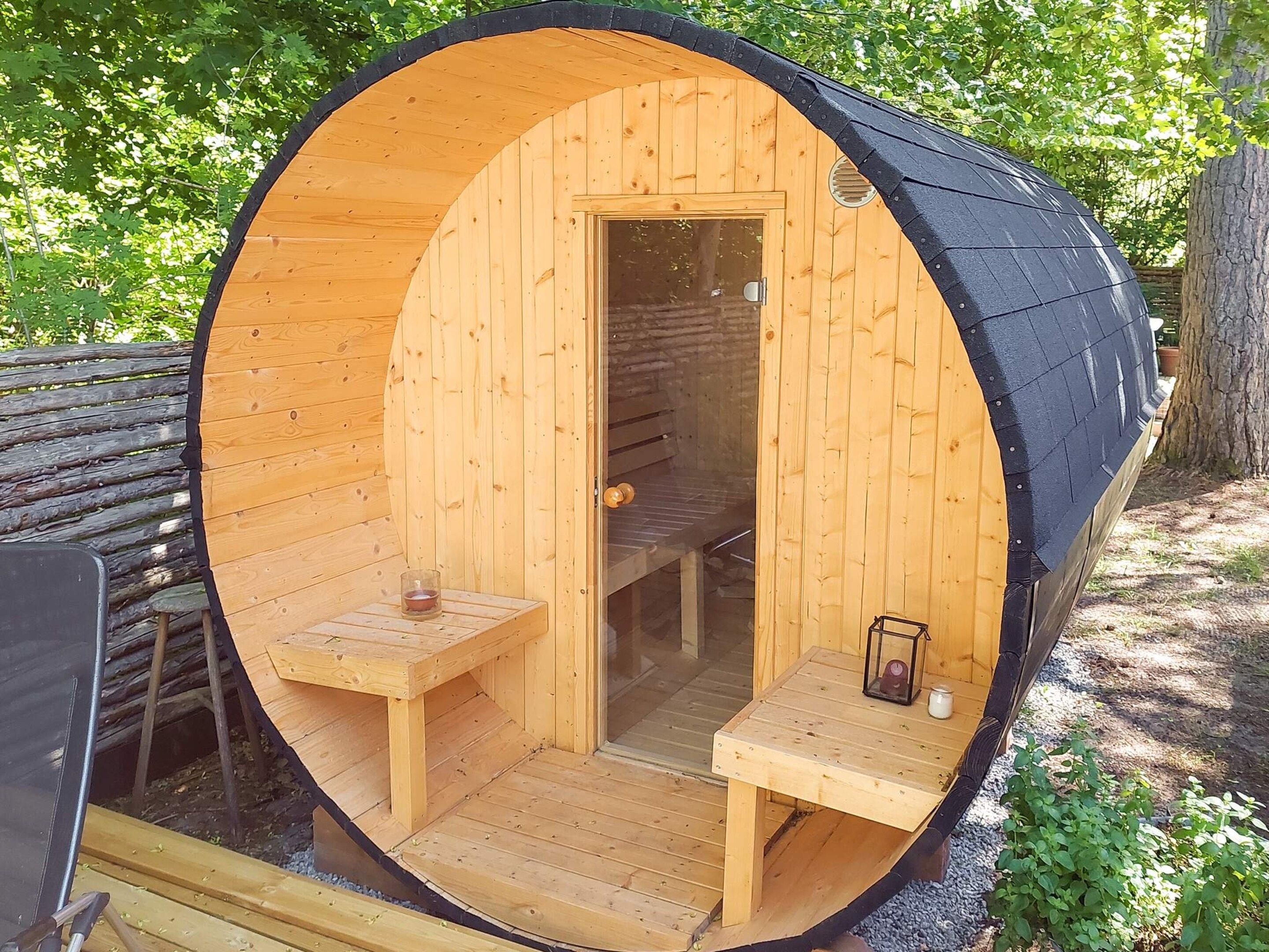 A wooden sauna with a bench and a table, a door, and a small table with a candle.