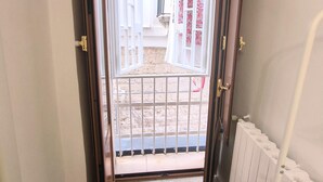 Pasillo con una puerta que da a un espacio exterior, suelo de baldosas y una reja metálica.
