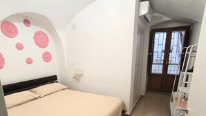 Un dormitorio con una cama, una pared blanca con diseños circulares, una puerta y una ventana.