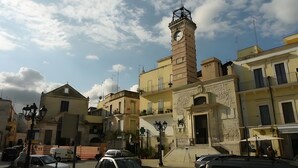 Un edificio histórico con una torre de reloj, una entrada central y una escalera que conduce a los pisos superiores.