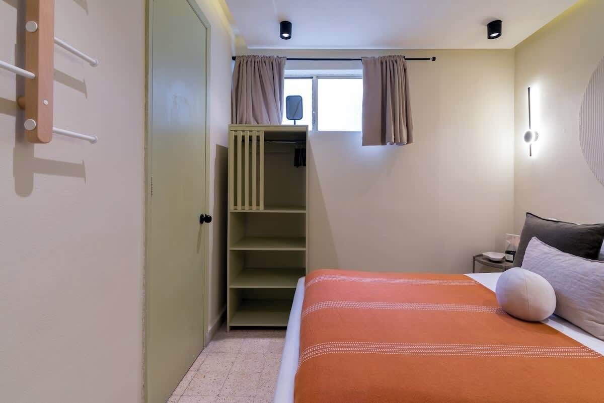 A bedroom with a bed, a wardrobe, a window with curtains, and a bedside table.