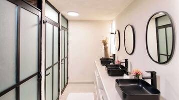 A modern bathroom with a long vanity, black sinks, and multiple mirrors.