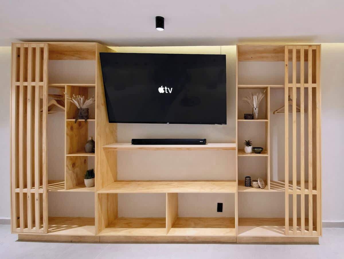 Uma unidade de entretenimento de madeira com uma TV de tela plana, prateleiras e compartimentos de armazenamento.