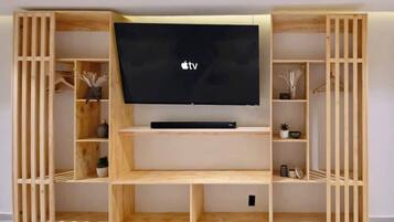 Uma unidade de entretenimento de madeira com uma TV de tela plana, prateleiras e compartimentos de armazenamento.