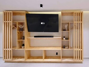 Un mobile in legno multifunzionale con televisore a schermo piatto, ripiani e vani contenitori.