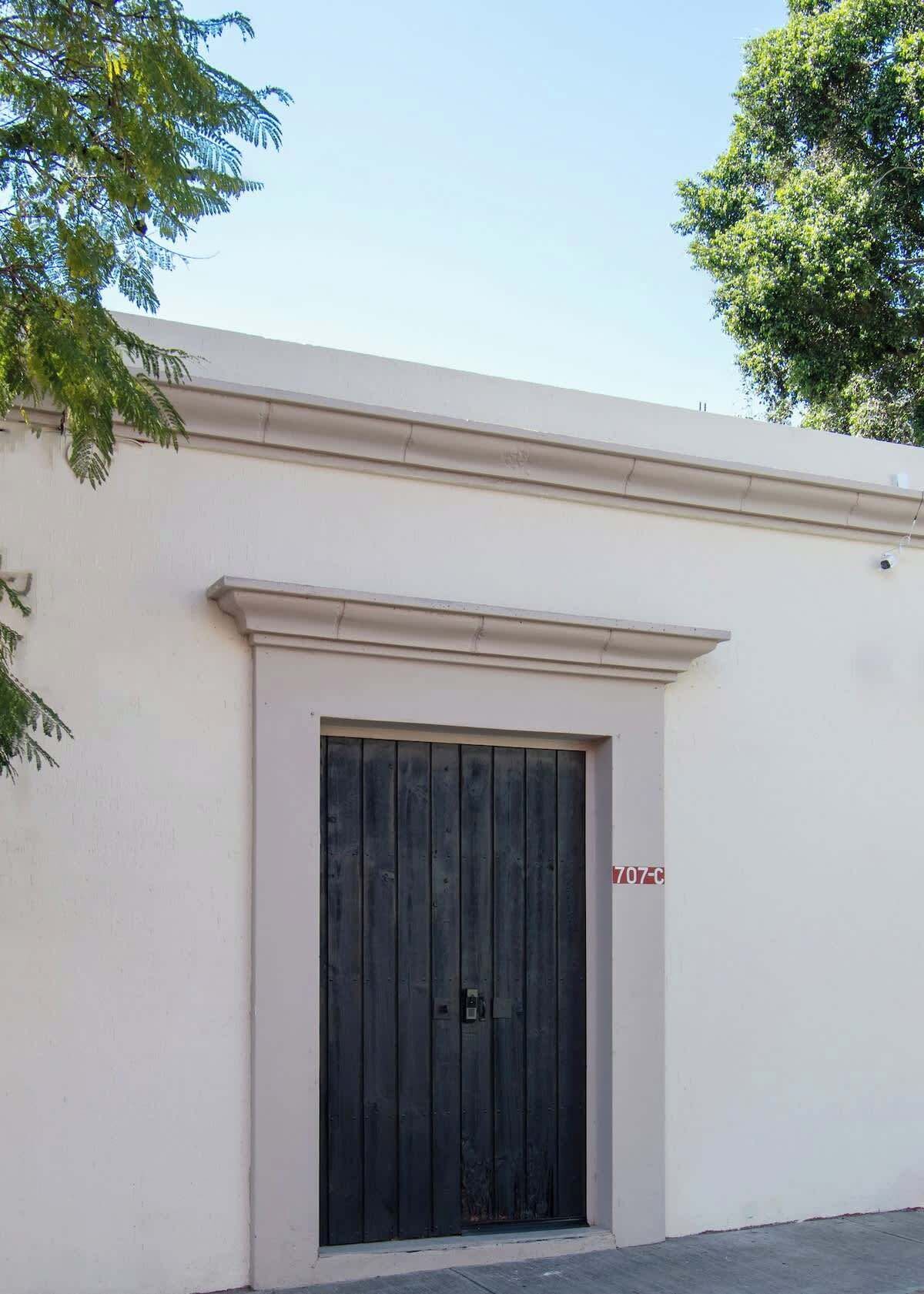 A building with a large black door, a white wall, and a small sign with '707-C'.