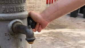 A hand turning a tap on a metal water fountain with inscriptions, set on a stone pavement. - Room 'Fichi D'India' with Wi-Fi and Air Conditioning (Modugno)