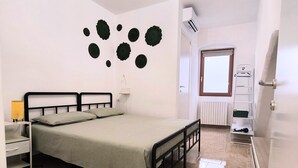 A bedroom with a bed, a nightstand, a lamp, a radiator, and a door leading to another room. - Room 'Fichi D'India' with Wi-Fi and Air Conditioning (Modugno)