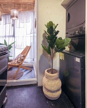 A kitchen with a built-in oven, a wicker planter with a large leafy plant, and a wooden chair with a patterned cushion. - Chic Stylish Design Flat in Roma Norte Prime Area (Mexico City)