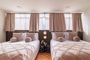 A double room with two beds, a wooden floor, and a window with curtains. - Chic Stylish Design Flat in Roma Norte Prime Area (Mexico City)