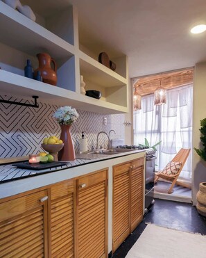 A kitchen with wooden cabinets, a herringbone backsplash, and a window with a chair outside. - Chic Stylish Design Flat in Roma Norte Prime Area (Mexico City)