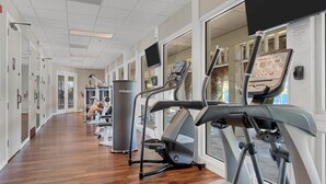 Un gimnasio con máquinas de cardio, máquinas de pesas y un espejo grande.
