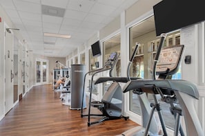 Ein Fitnessstudio mit Laufbändern, Krafttrainingsgeräten und einer Spiegelwand.