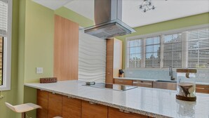 Una cocina con una isla central, armarios de madera, un lavamanos de acero inoxidable y una ventana con persianas.