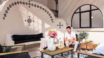 A modern interior with a curved wall, a black sofa, a wooden coffee table, and a small side table with a vase of flowers.