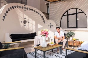 A modern interior with a curved wall, a black sofa, a wooden coffee table, and a small side table with a vase of flowers.