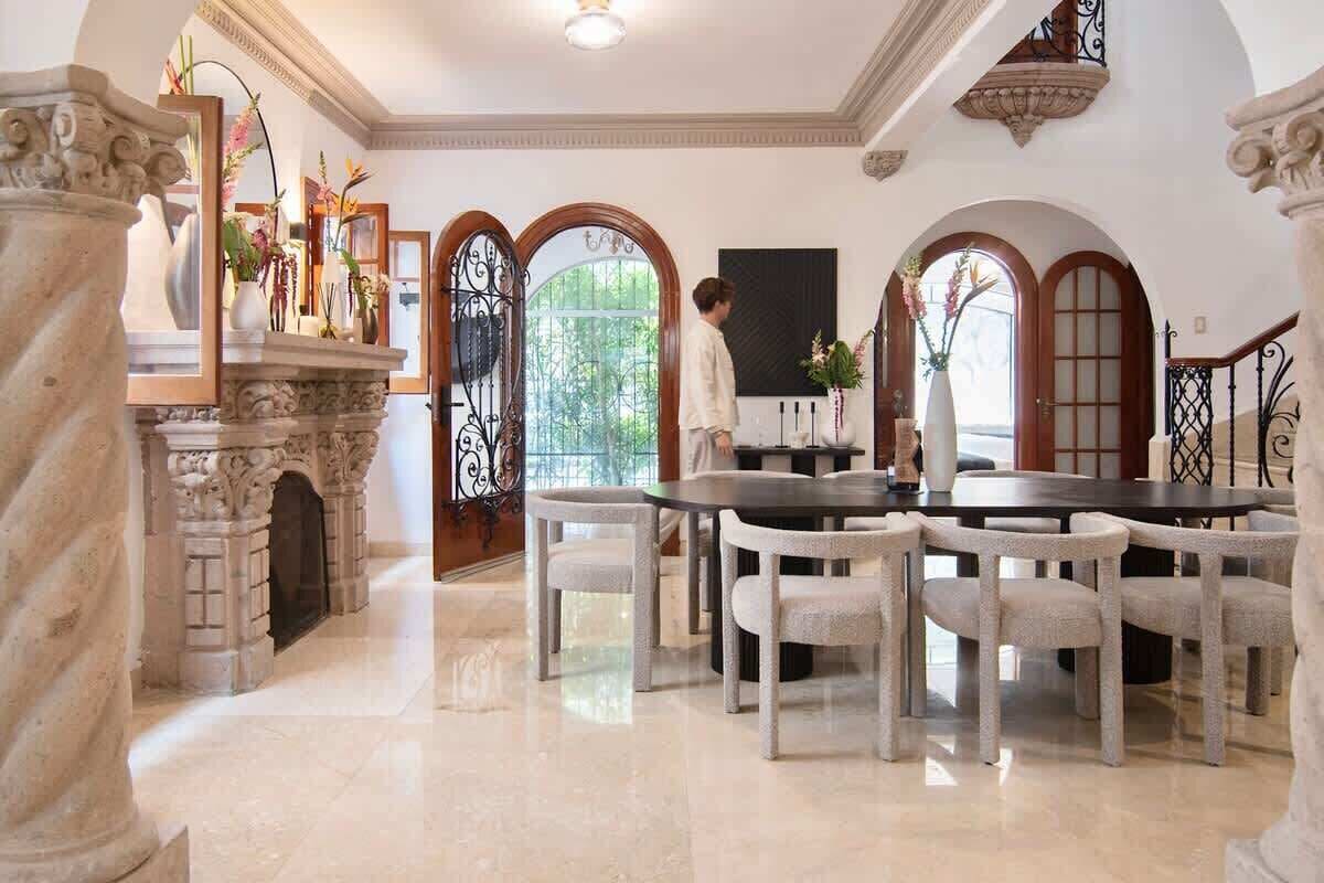 A dining area with a marble floor, a fireplace, and a table with chairs.