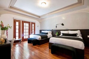 A hotel room with two beds, a desk, a chair, and a large window with a view.
