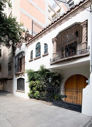 A building with a white facade, multiple balconies with wrought iron railings, and a wooden door.