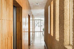 A corridor with wooden paneling and a textured wall, leading to a glass door. - Location- Design And Comfort Fully equipped (Ciudad de México)