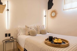 A neatly arranged bedroom with a bed, bedside table, wall decor, and a tray with candles and lemons. - Location- Design And Comfort Fully equipped (Ciudad de México)