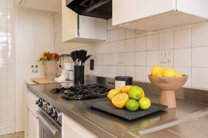 A kitchen with a gas stove, a cutting board with fruits, a coffee maker, and a bowl of lemons. - Location- Design And Comfort Fully equipped (Ciudad de México)