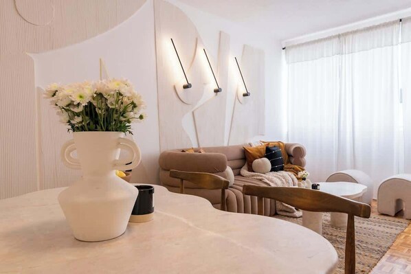 A modern living room with a round table, a vase of flowers, a sofa, and abstract wall art. - Location- Design And Comfort Fully equipped (Ciudad de México)