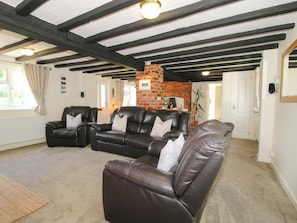 A living room with a fireplace, leather sofas, and exposed wooden beams.