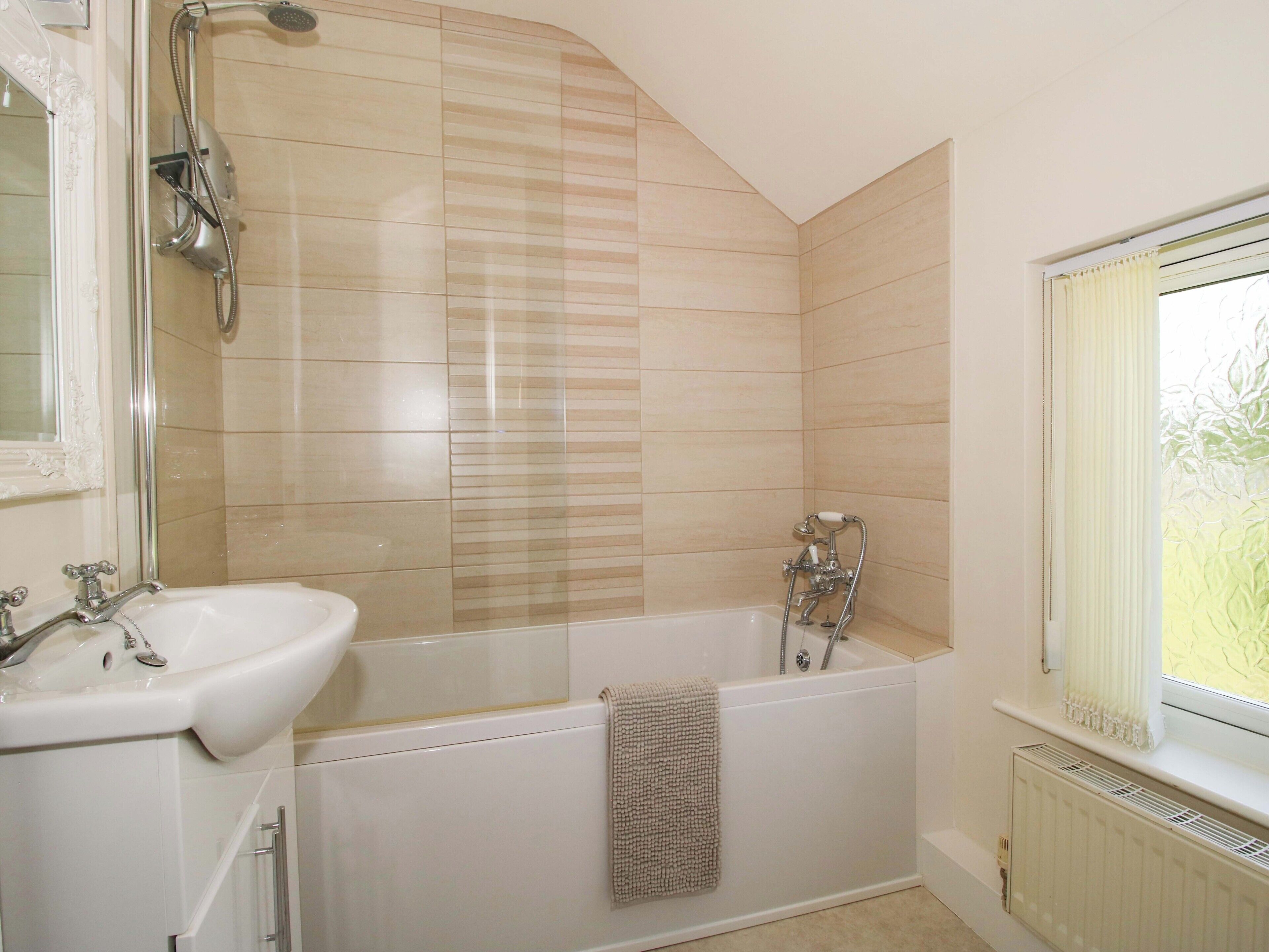 Un baño con bañera, lavabo y ventana.