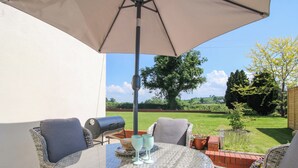 A round wicker table with chairs, a grill, and a table umbrella. - Fron-haul (Llansantffraid-ym-Mechain)