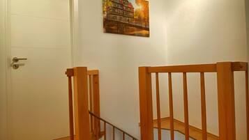 Una escalera con barandillas de madera, una puerta y un cuadro colgado en la pared.