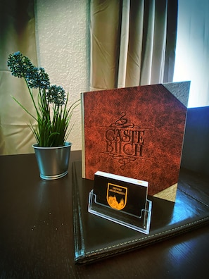 A table with a potted plant, a red textured card, and a black card with a logo.