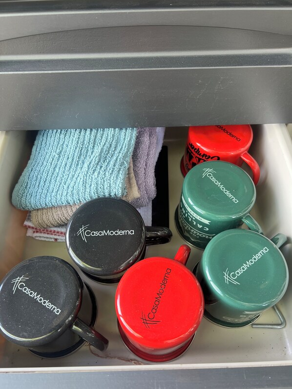 A drawer containing various items including mugs and a towel.