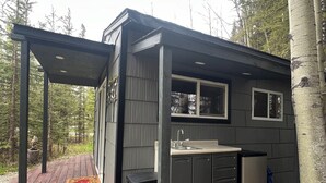 Una cabaña pequeña con cocina, terraza y espacio exterior cubierto.