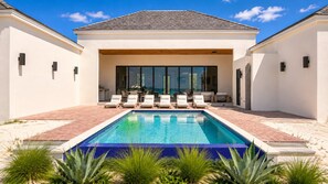 A modern house with a swimming pool, outdoor seating, and a patio area.
