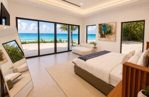 Un dormitorio con una ventana grande con vistas a la playa, una cama, una silla y una mesita.