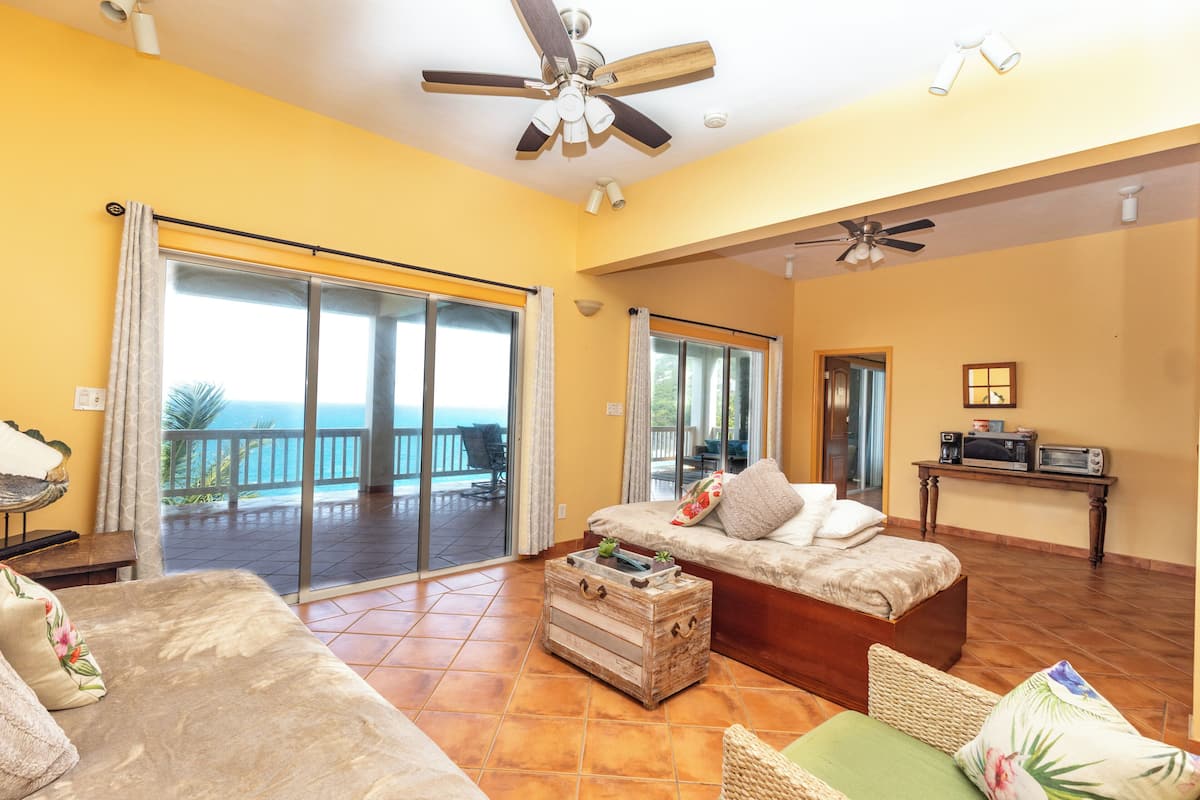A spacious living area with a sofa, a coffee table, and a balcony with a view.