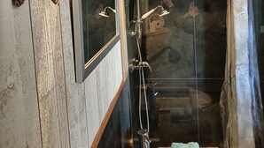 A bathroom with a wooden wall, a starfish decoration, a mirror, a shower, and a towel on a stool. - Cabin “Robin Hood’s Cabin” with Private Terrace and Nordic Bath (Foulcrey)